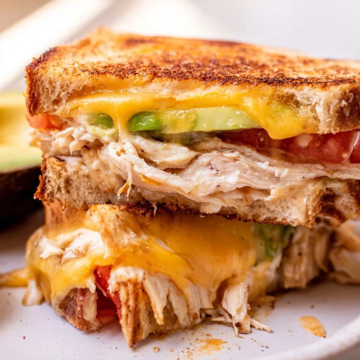 Warm chicken avocado melt sandwich on a plate with crispy bread and creamy avocado filling