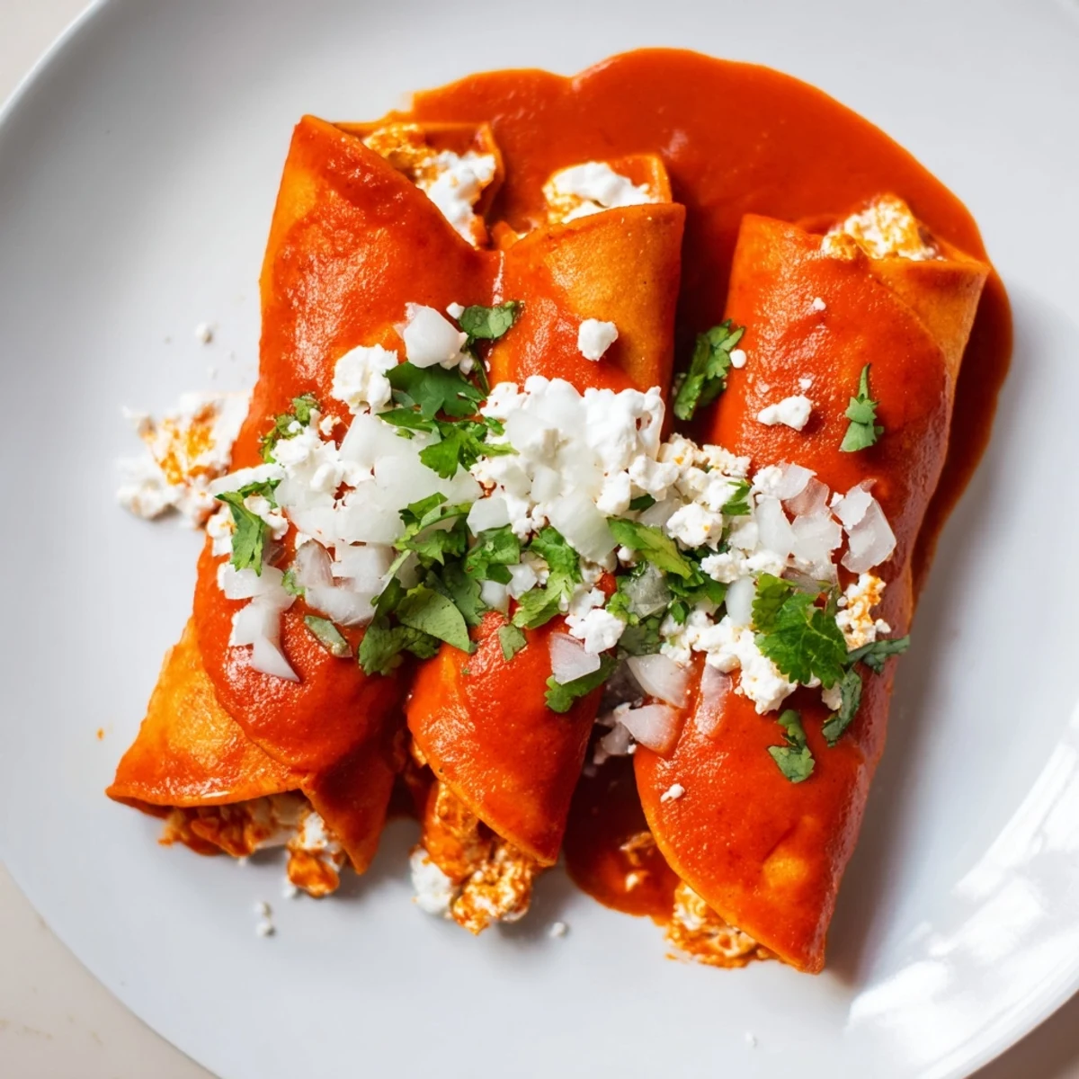 Golden corn tortillas dipped in vibrant tomato salsa make these entomatadas irresistible and cheesy.