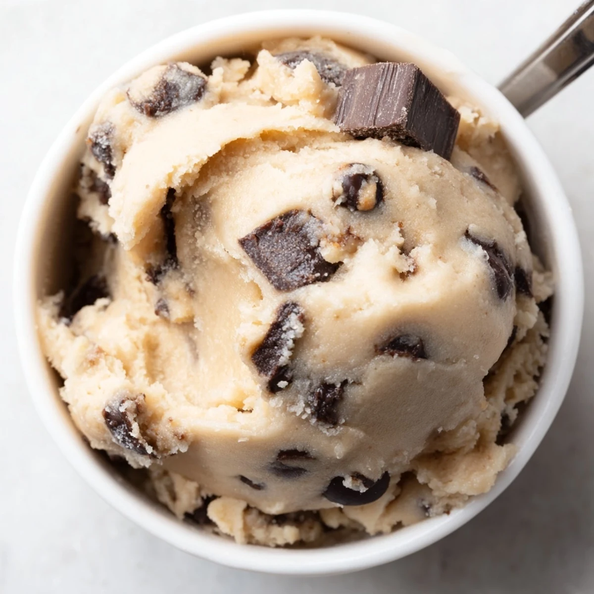 Creamy chocolate chip cookie dough loaded with chips in a rustic ceramic bowl.