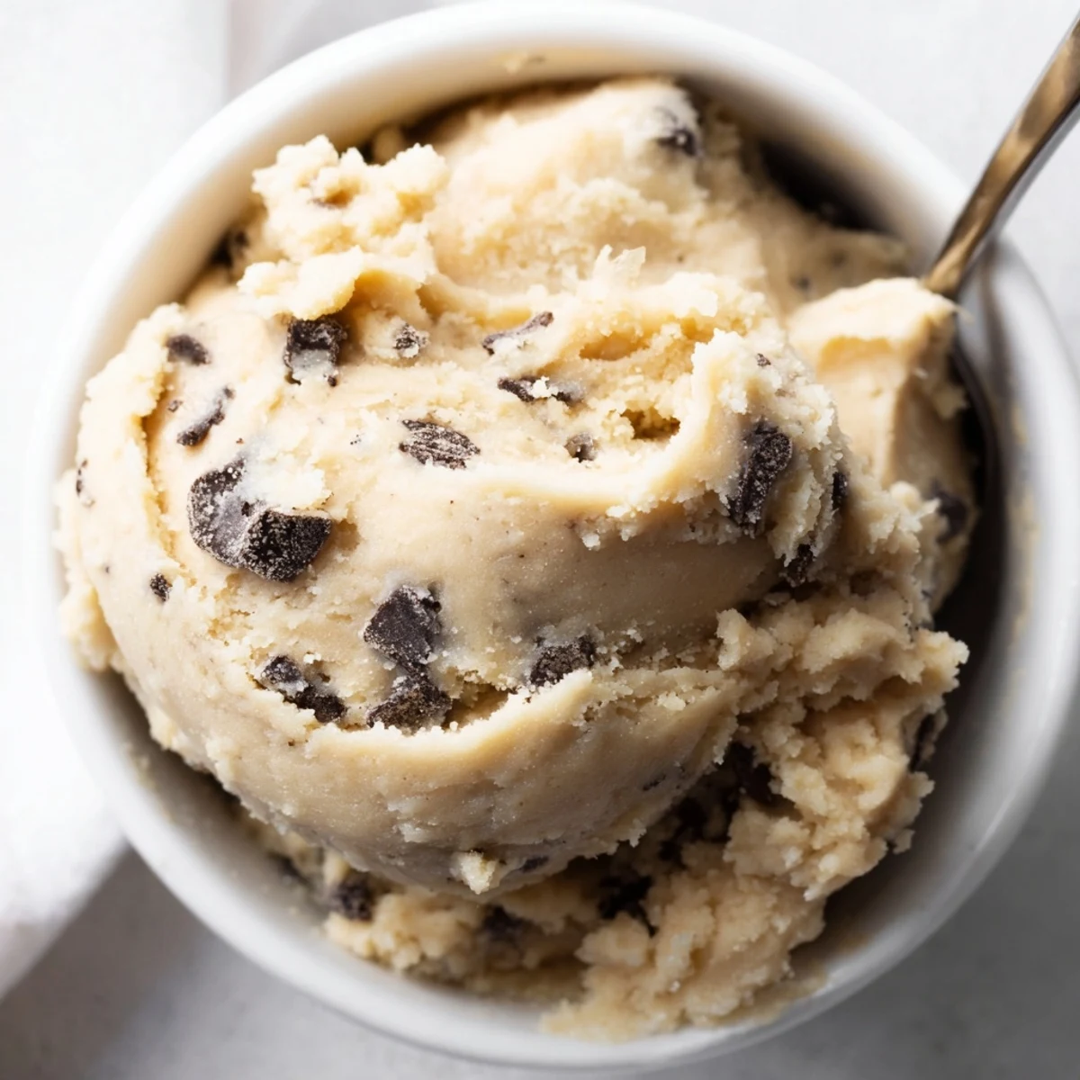 Spoonful of safe-to-eat chocolate chip cookie dough studded with melty chocolate morsels.