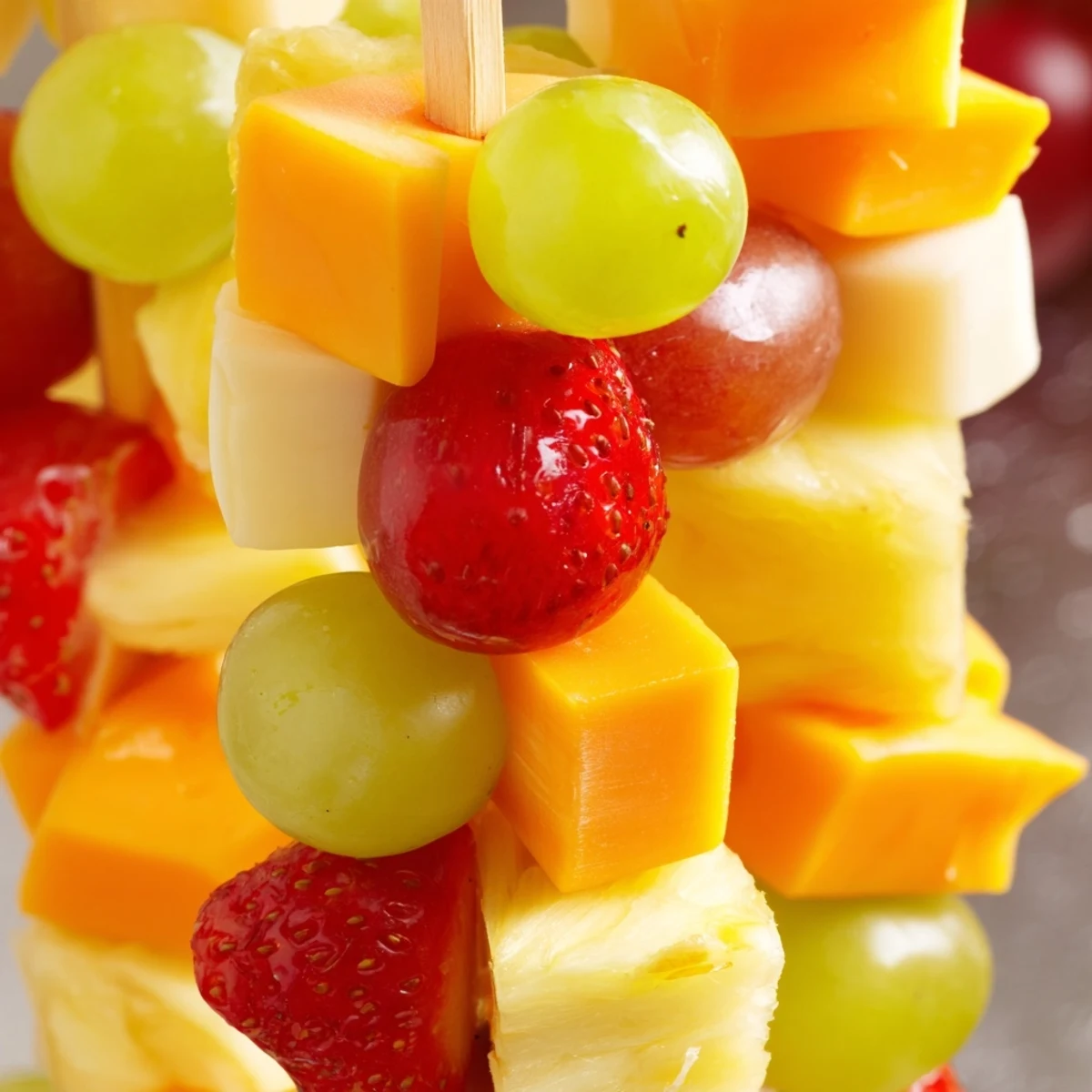 Fresh fruit and cheese kabobs featuring strawberries pineapple and Monterey Jack on wooden skewers