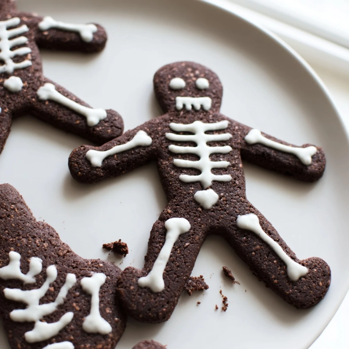 Chocolate cinnamon skeleton cookies with white icing bones on a parchment-lined baking sheet