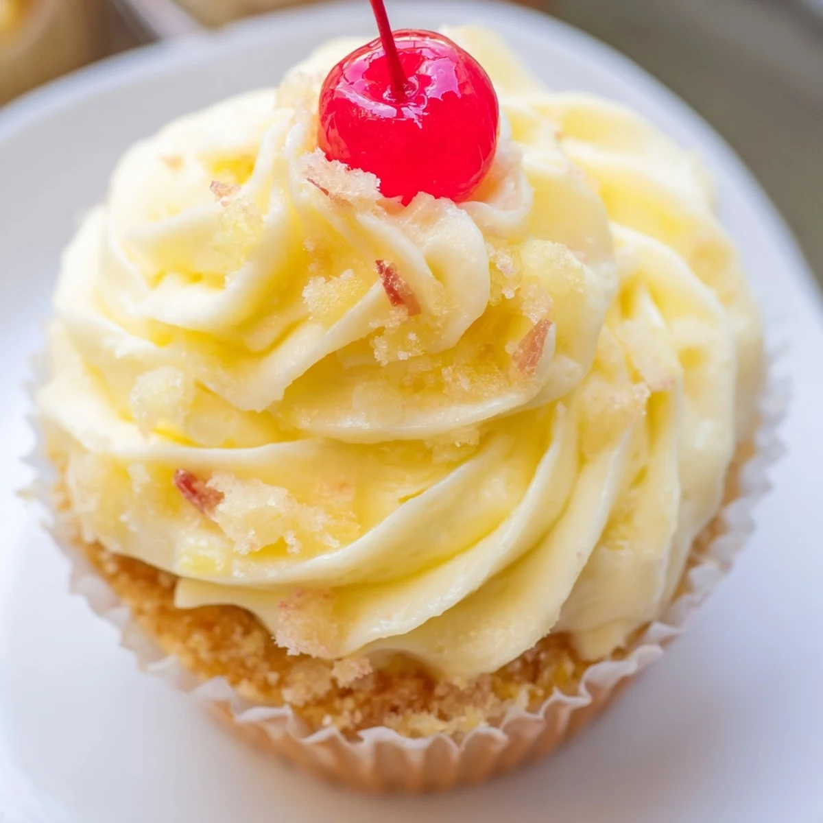 Golden Dole Whip Cupcakes topped with fluffy pineapple whipped frosting and a cherry