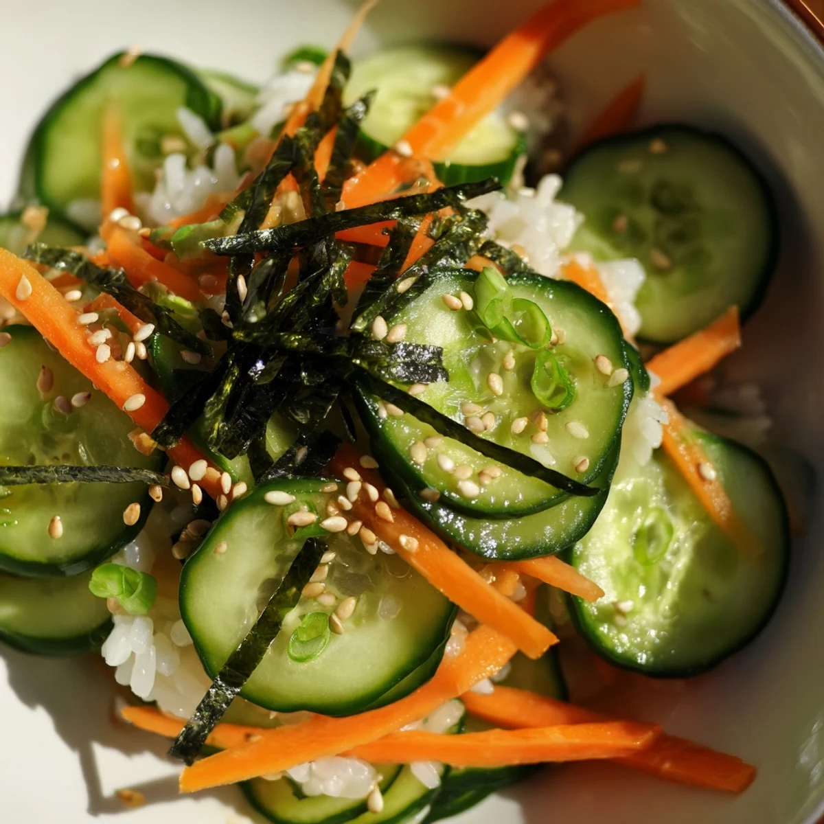 Bright bowl of chilled cucumbers, seasoned rice, toasted sesame in a Sushi Cucumber Salad