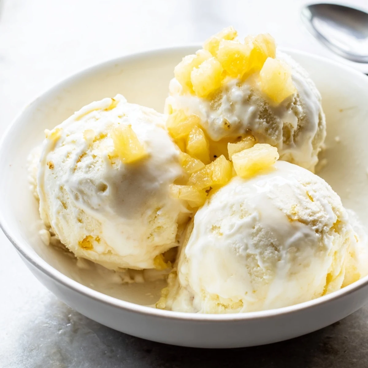 Creamy Pineapple Ice Cream topped with toasted coconut and rum drizzle.