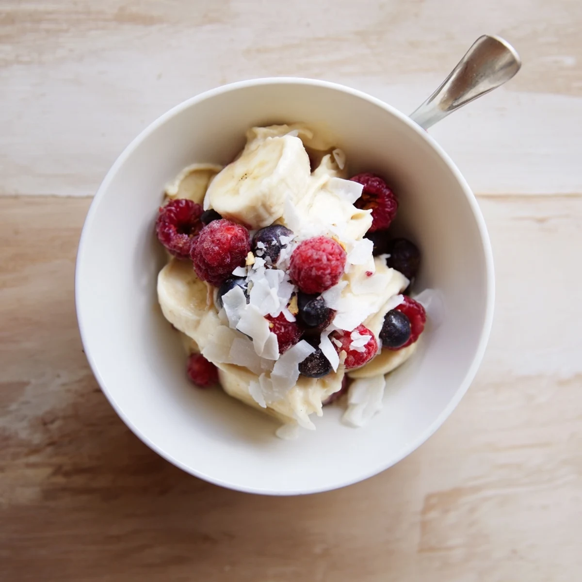 Creamy healthy nice cream recipe served in a bowl topped with fresh mixed berries and coconut flakes