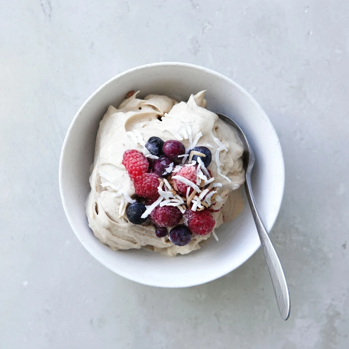 Thick swirled healthy nice cream recipe displaying soft serve texture garnished with colorful fresh fruit toppings