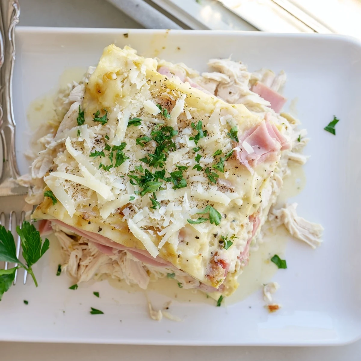 Golden chicken cordon bleu lasagna with bubbling mozzarella and fresh parsley garnish