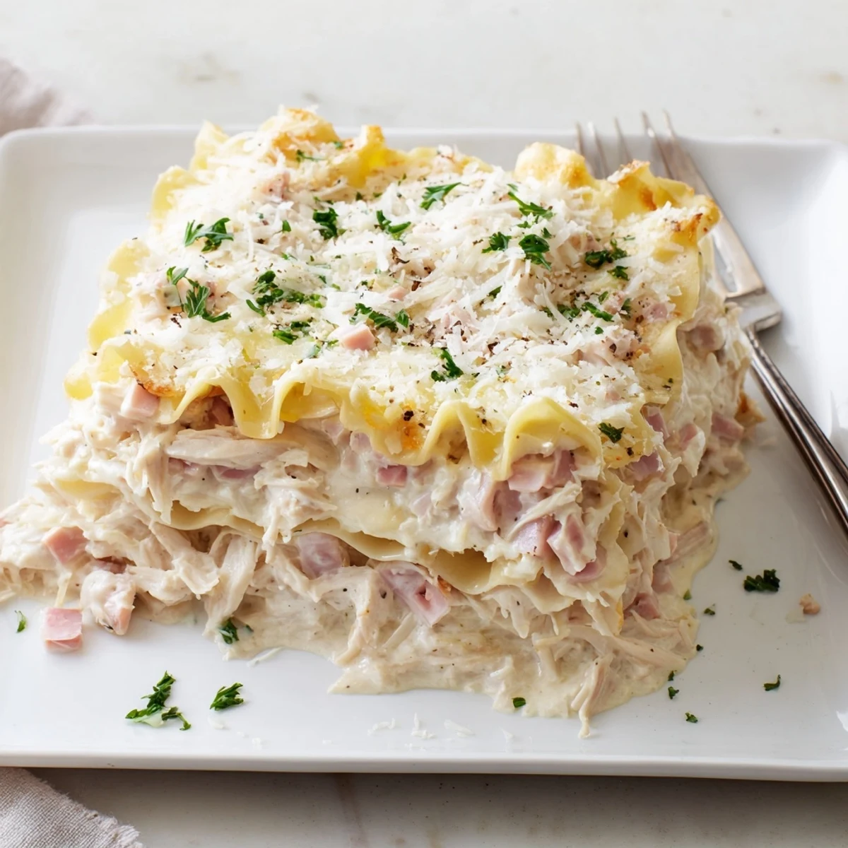 Baked chicken cordon bleu lasagna squares plated with crispy edges and melted cheese