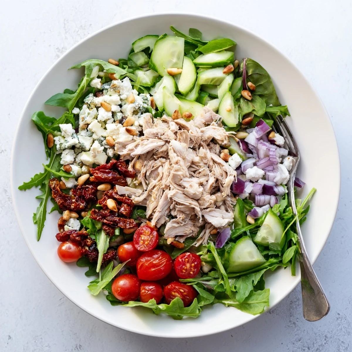 Mediterranean chicken salad featuring sun-dried tomatoes, crisp cucumber, and tangy feta cheese topping