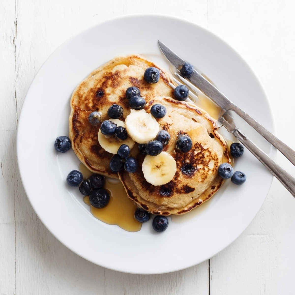 Plate of warm protein banana pancakes served with berries and Greek yogurt topping