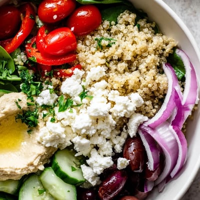 A vibrant Mediterranean Quinoa Bowl with hummus, crisp cucumbers, and roasted red peppers served for lunch.