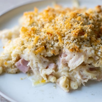 Freshly baked Chicken Cordon Bleu Casserole served with green beans on a rustic wooden table.