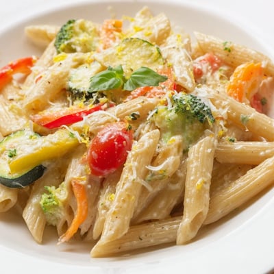 A close-up of Creamy Pasta Primavera with Vegetables, sautéed zucchini, peppers, and al dente penne.