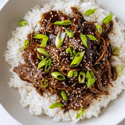 A slow cooker full of tender Crock Pot Korean Beef, garnished with sesame seeds and green onions for a flavorful weeknight meal.
