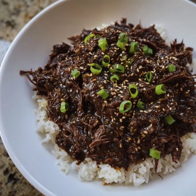 Crock Pot Korean Beef simmered in a rich, aromatic sauce served over fluffy rice with a sprinkle of sesame seeds.