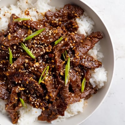 Steaming Ultimate Slow Cooker Mongolian Beef in a slow cooker, tender beef coated in glossy savory-sweet sauce, paired with sesame rice and vegetables.
