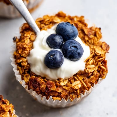 Warm, moist Baked Oatmeal Cups with Greek Yogurt garnished with fresh berries on a rustic wooden board.