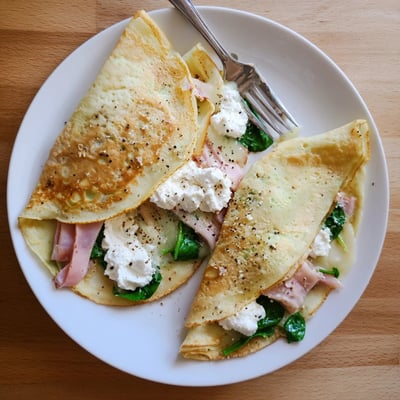 Delicate French savory crepes rolled with creamy spinach and grated cheese topping