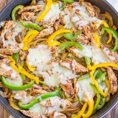 One-pan chicken cheesesteak skillet featuring caramelized onions and gooey melted provolone cheese slices