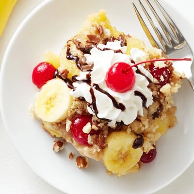 Fresh from oven Banana Split Dump Cake topped with whipped cream and cherries