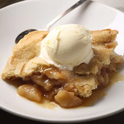 Rustic dessert of Southern banana cobbler recipe topped with melting vanilla ice cream and cinnamon.